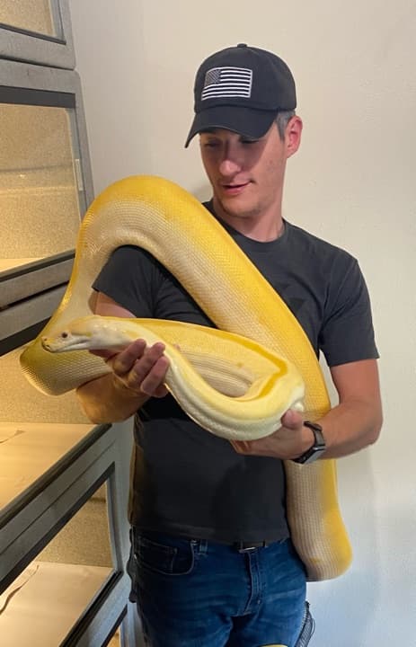 Jonathan, owner of Castle Reptiles and lead developer of Scutely, holding an albino reticulated python